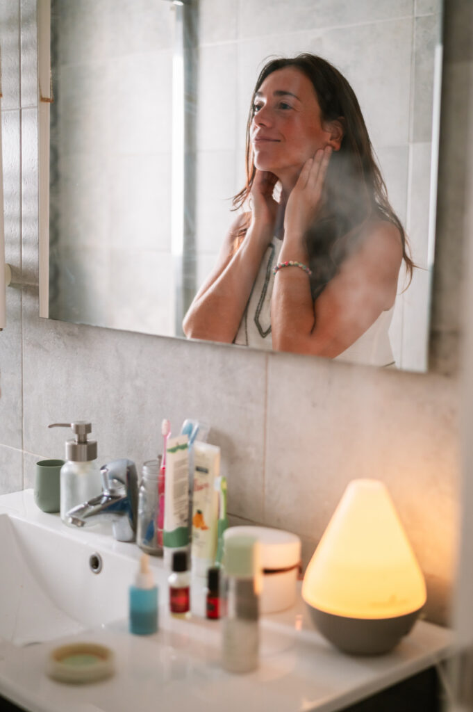 mujer utilizando aceites esenciales como rutina facial en el baño